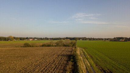 Dramatic and colorful sunrise or sunset sky over a grassy green farmfield shot from drone high up. High quality photo