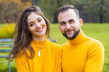 Couple of lovers dressed in yellow turtlenecks in the park hugging