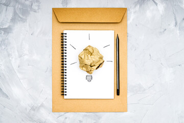 Light bulb symbol made of a crumpled paper ball and a sketch on a spiral notebook. Creative process concept.