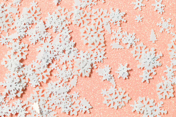 Light pink background with snow glitter and sequins. Flat lay style. Winter soft texture with snowflakes for creating projects and designs