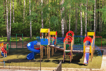 bright colorful children's playground in the summer in a birch grove