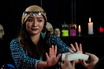 Portrait of Asian beautiful Gypsy fortune teller woman in dark room refuse and say no to receive...