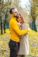 Couple of lovers dressed in yellow turtlenecks in the park hugging