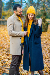 Couple dressed in yellow turtlenecks and yellow hats in the park in autumn