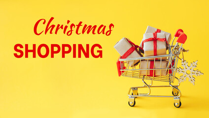 Christmas shopping concept. Supermarket stroller with Christmas gift boxes on yellow background. - 393507469