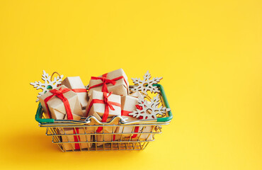 Christmas gifts and New Year symbols in a shopping basket on yellow background with copy space. - 393507477