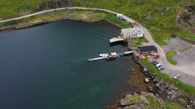 Aerial view of a group of people and a boat ready for a whale safari in the Sto town, in Vesteralen islands, cloudy day, in Norway - tilt up, drone shot