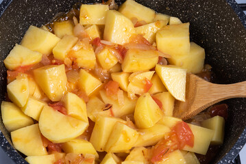 Cooking a traditional Italian vegetable stew with potatoes, eggplants and peppers in a frying pan - Neapolitan cianfotta.