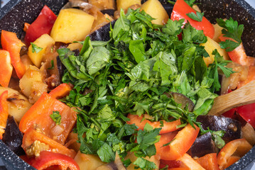 Cooking a traditional Italian vegetable stew with potatoes, eggplants and peppers in a frying pan - Neapolitan cianfotta.