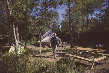a man with a backpack on a nature excursion holds a gas lamp in a camp in the woods