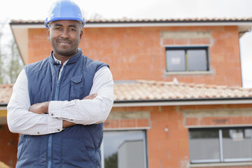 proud and confident constructor standing in front of new house