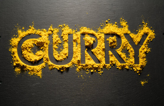Word "Curry" from dry curry powder on black background.