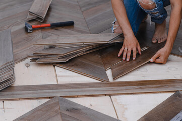 Man laying parquet flooring - closeup on male hands. worker joining parquet floor