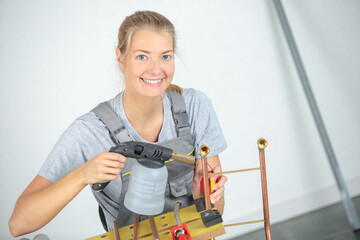 woman using a blowtorch on copper pipes