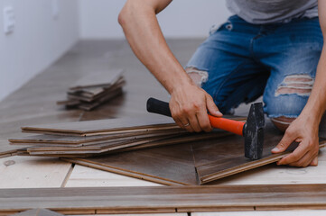Man laying parquet flooring - closeup on male hands. worker joining parquet floor