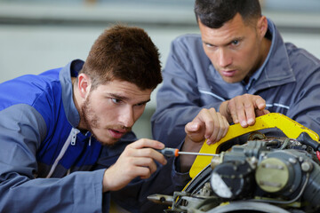 Fototapeta na wymiar apprentice fixing mechanical part with screw driver