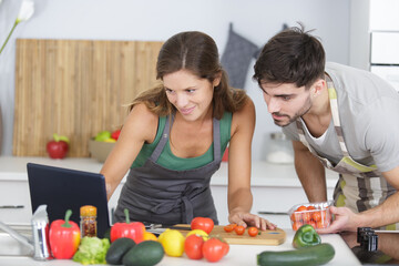 couple cooking at home reading recipe from a tablet