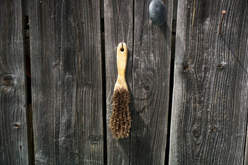 Closeup of a brush with a wooden handle hanging on the wooden fence