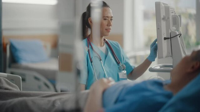 Hospital Ward: Portrait of Professional Chinese Head Nurse Doing Patient Vital's Checkup, Monitoring Equipment, Medicine Delivery. Nurse Talks to Person Getting Well after Successful Surgery