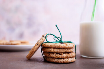 Fresh delicious milk in a glass bottle on a textured background with chocolate cookies on a white plate.