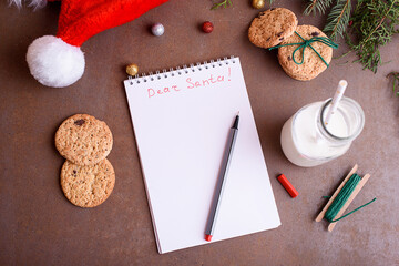 Delicious cookies with chocolate on a white plate, milk, santa hat, muck up for text. Letter and cookies for Santa.