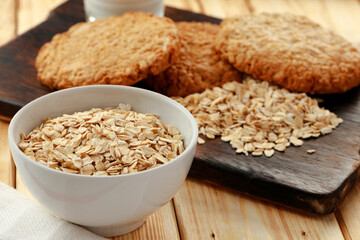 Oat cookies and oat flakes on wooden surface