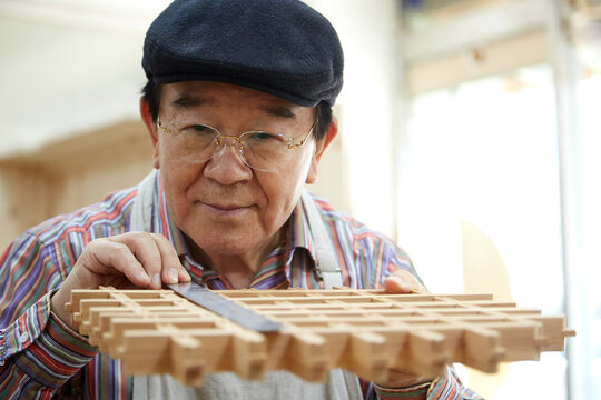 old man focusing on a wooden frame