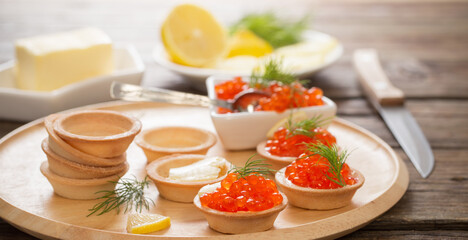 cooking tartlets with red caviar on wooden table