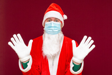 Santa Claus medical mask making a stop gesture with his hands on red background