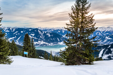 Zell am See and Schmitten town at Zeller lake in winter. View from Schmittenhohe mountain, snowy ski resort slope in the Alps mountains, Austria. Stunning landscape, snow and sunset sky near Kaprun