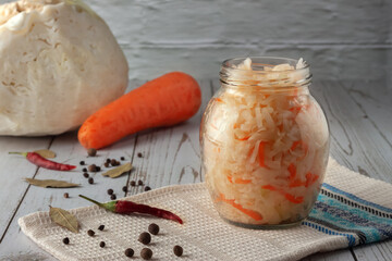 Sauerkraut with carrots and spices in a jar. Horizontal top view, rustic style