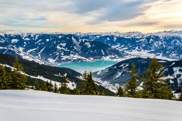 Zell am See and Schmitten town at Zeller lake in winter. View from Schmittenhohe mountain, snowy ski resort slope in the Alps mountains, Austria. Stunning landscape, snow and sunset sky near Kaprun