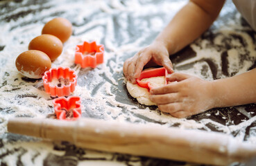 Kids hands cutting out shapes and making cookies. Making biscuits for christmas decorations. Children's art project, a craft for children.