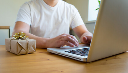 Fototapeta premium A man searches the Internet for gifts on a laptop. Online shopping concept