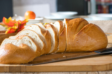 A loaf of white bread on a wooden cutting board with knife