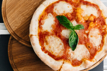 juicy appetizing pizza on top on a wooden board with fresh basil leaves