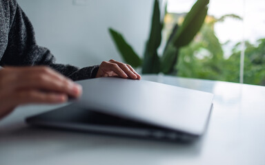 Closeup image of hands close and open a laptop computer on table after finished using it
