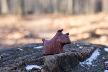 Lonely toy dog on a snow covered stump in the autumn forest brightly lit by the sun; the concept of solitude, unity with nature, tranquility
