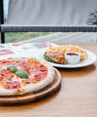 pizza dishes, french fries, grilled chicken and aperol on the table