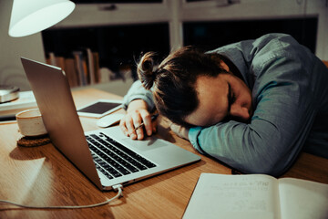 Tired caucasian businessman sleeping at office desk after a long night shift of work, working in...