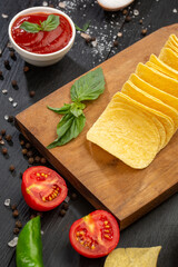 Potato chips and vegetables in composition on black background