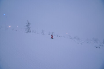 Skateboarder on the slope in snowy weather 