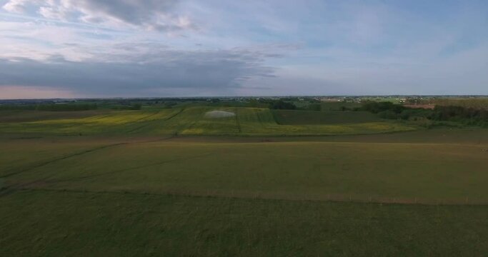 Big Water Sprinkler on Rape Field at The Summer Evening in South Sweden Sk&aring;ne &Ouml;sterlen K&aring;seberga, Aerial Forward Slow