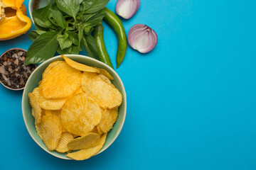 Potato chips and spices in composition on blue background