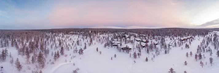 Rolgordijnen Visit Lapland Holidays. Aerial drone panorama shot of the forest covered in snow winter and the village inside the Arctic Circle. Lapland, Finland. Winter sunrise. Igloos and cabins covered with snow © oluuuka