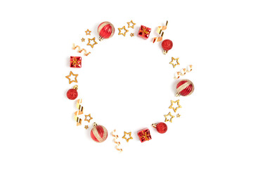 Wreath made of red Christmas toys and gold confetti. Minimalist festive frame on a white background.