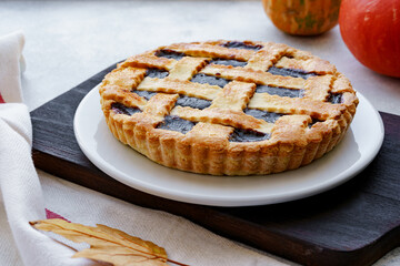 Berry tart pie and orange pumpkin on wooden table