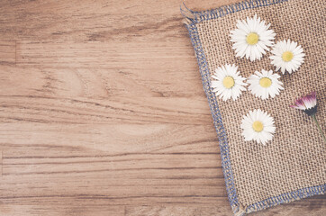 High angle shot of Daisy flowers on a piece of cloth on a wooden surface