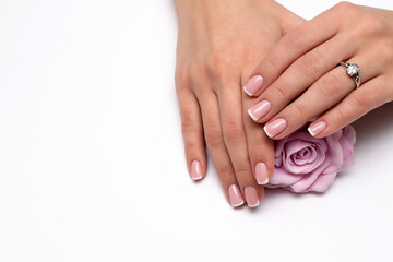 Wedding French manicure on short square nails with a pink rose in hand. Ring on a finger.