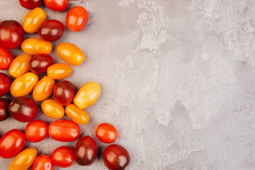 Cherry tomatoes on gray marble background. Copyspace.